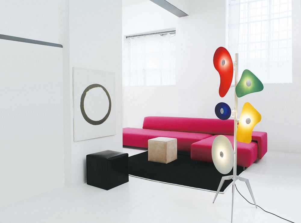 Moderne Stehlampe mit bunten Lampenschirmen im minimalistischen Wohnzimmer mit pinkem Sofa und Kunstwerk.