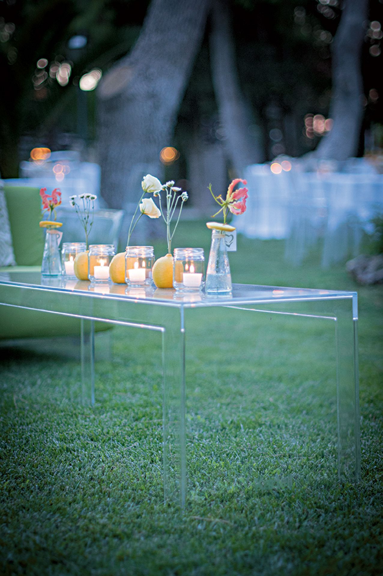 Transparenter "Invisible Side" Tisch von Kartell, niedrig, mit Dekoration im Freien auf Rasen.