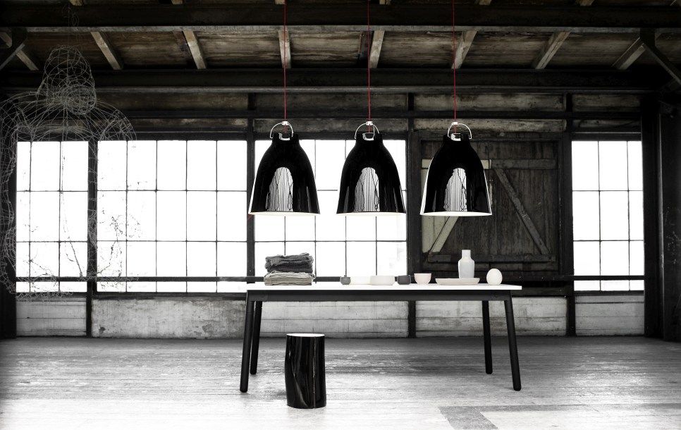 Drei Fritz Hansen Caravaggio Pendelleuchten in Schwarz über einem Esstisch in einem Loft.