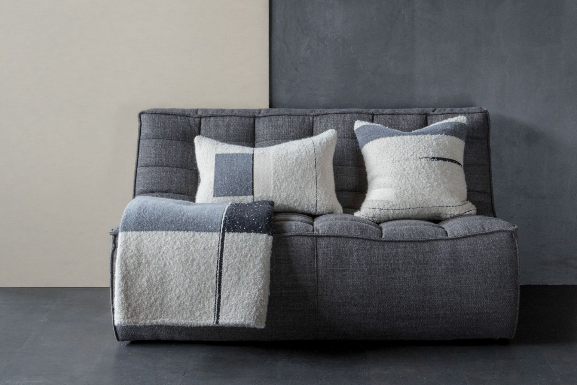 Urban Überwurf von Ethnicraft auf grauem Sofa mit passenden Kissen, modernes Wohnaccessoire.