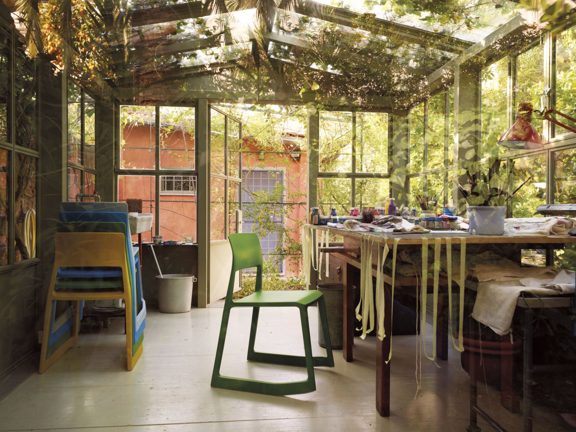 Grüner Tip Ton RE Stuhl von Vitra in einem hellen Atelier mit Glaswänden und Werkstatttisch.