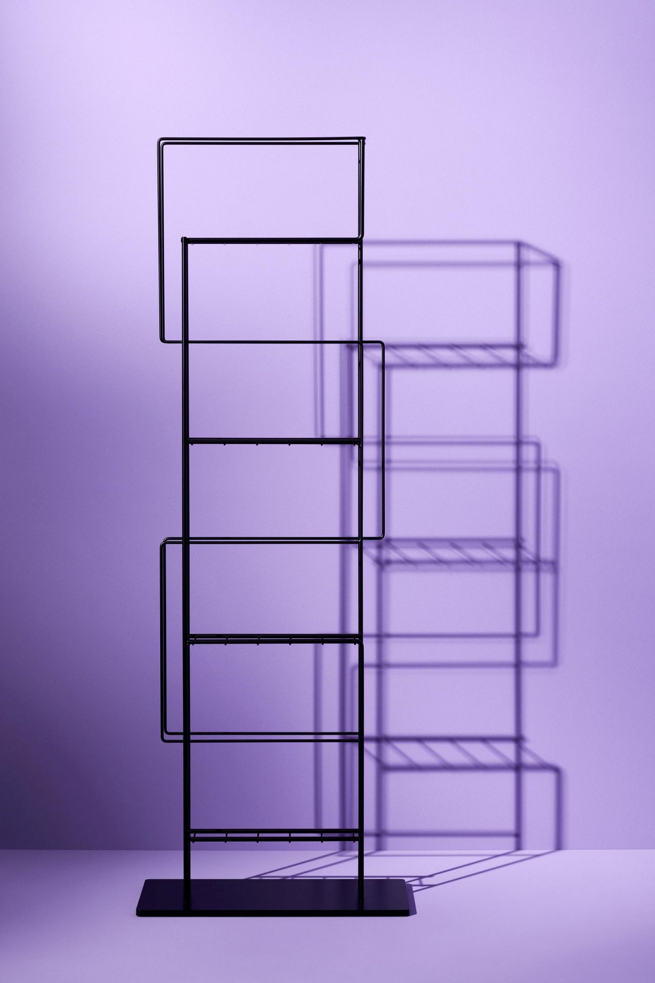 Schwarzer Revue Zeitungs- und Prospekthalter von Schönbuch vor lila Hintergrund, modernes Design für Zeitschriften und Broschüren.