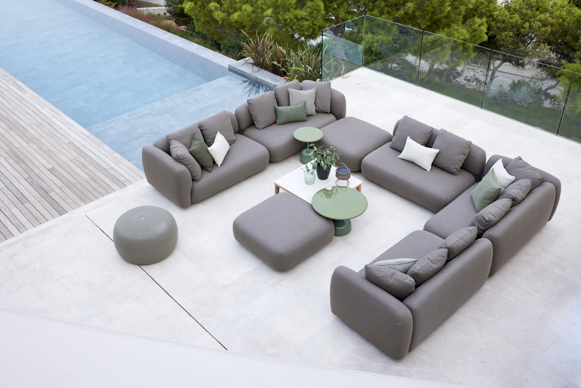 Capture Outdoor Sofa von Cane-Line, graues modulares Lounge-Set mit Kissen und Beistelltischen am Pool.