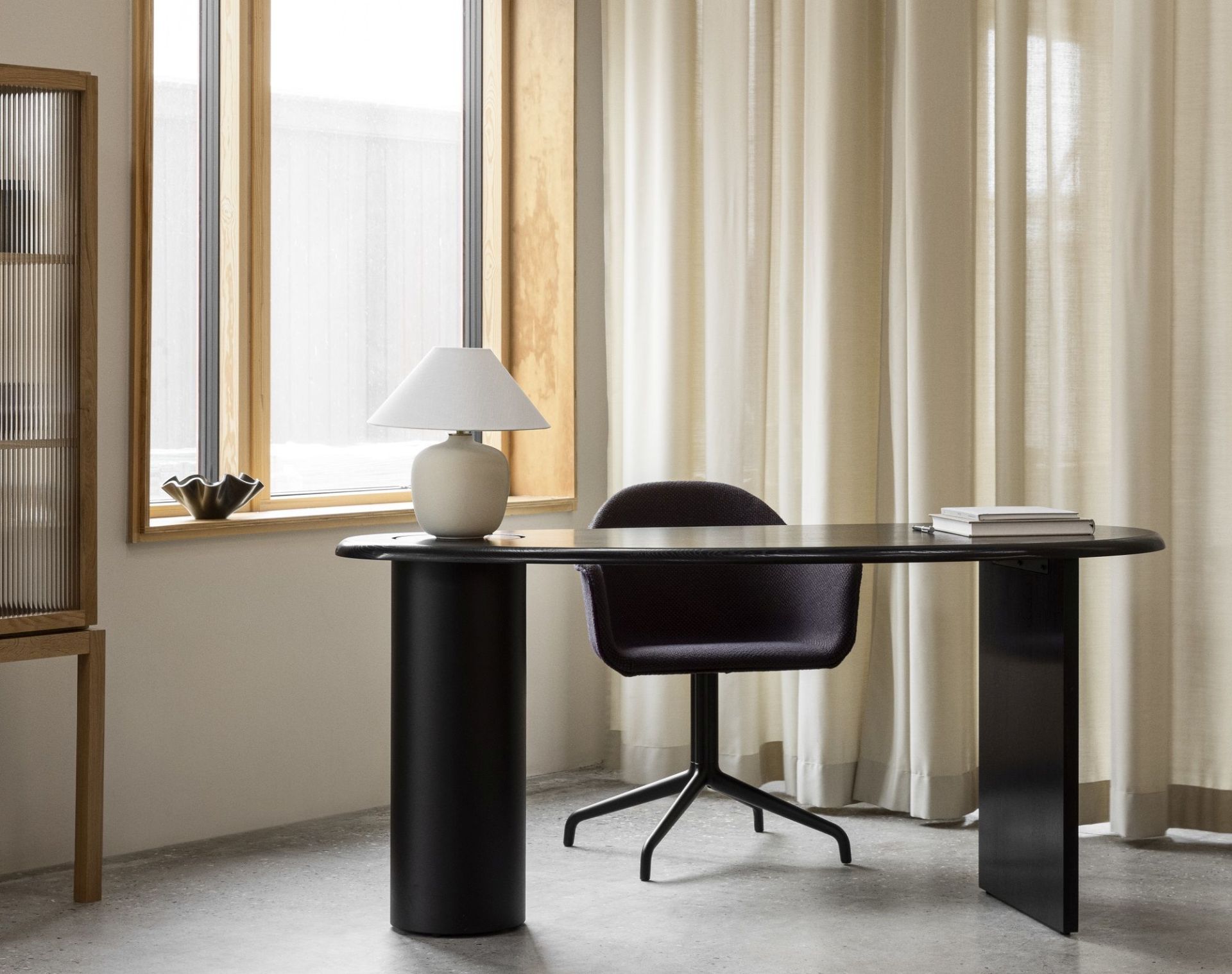 Audo Copenhagen Eclipse Desk Schreibtisch in Schwarz mit Stuhl und Lampe vor Fenster.