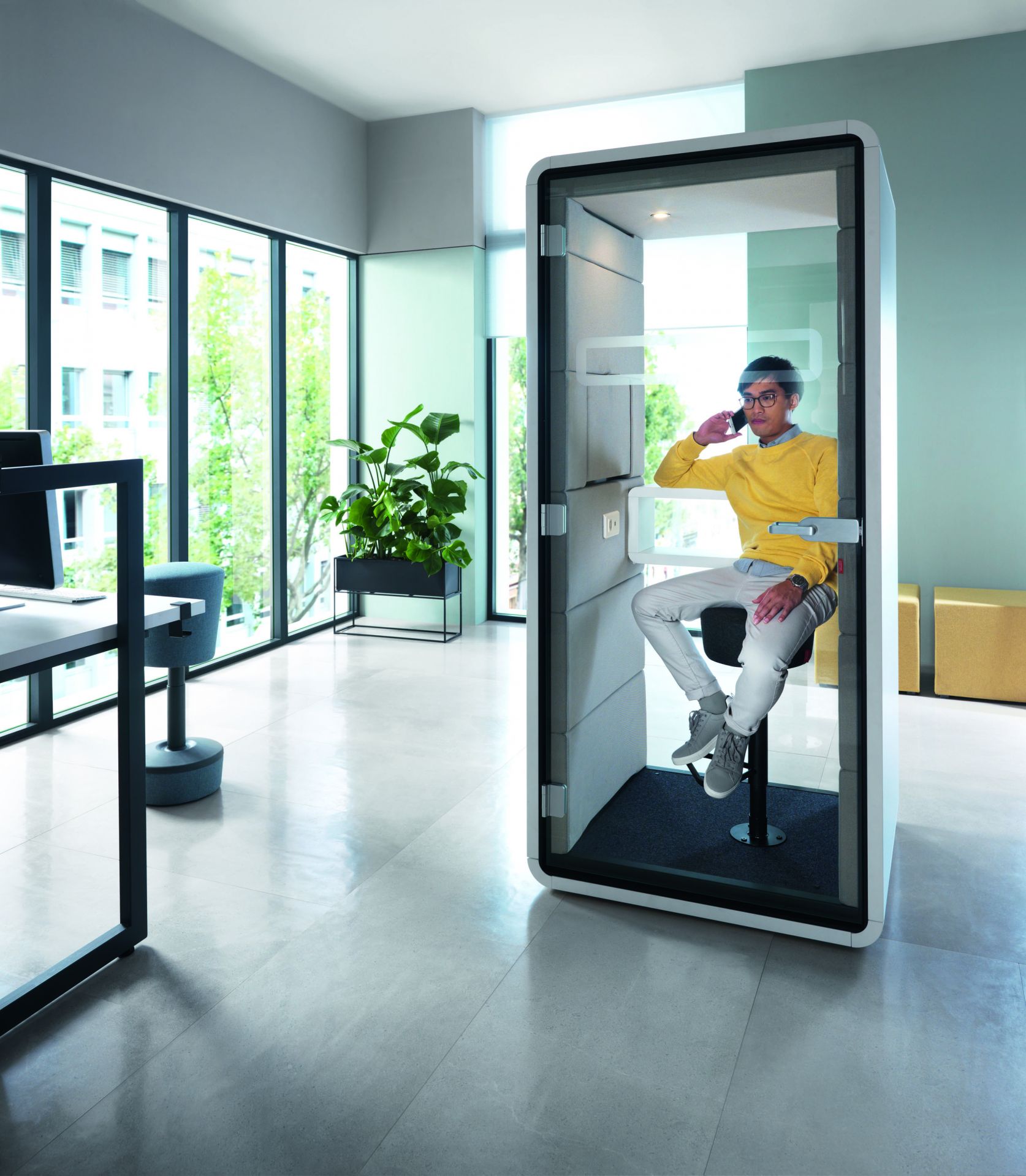 Mann telefoniert in einer HushPhone Meetingbox von Mikomax, einer schallisolierten Telefonzelle für Büros.