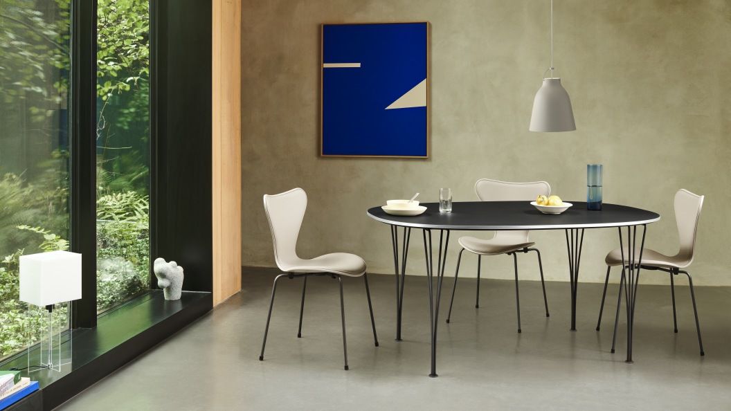 Esszimmer mit Fritz Hansen Caravaggio Pendelleuchte in Grau über einem Esstisch mit Stühlen.