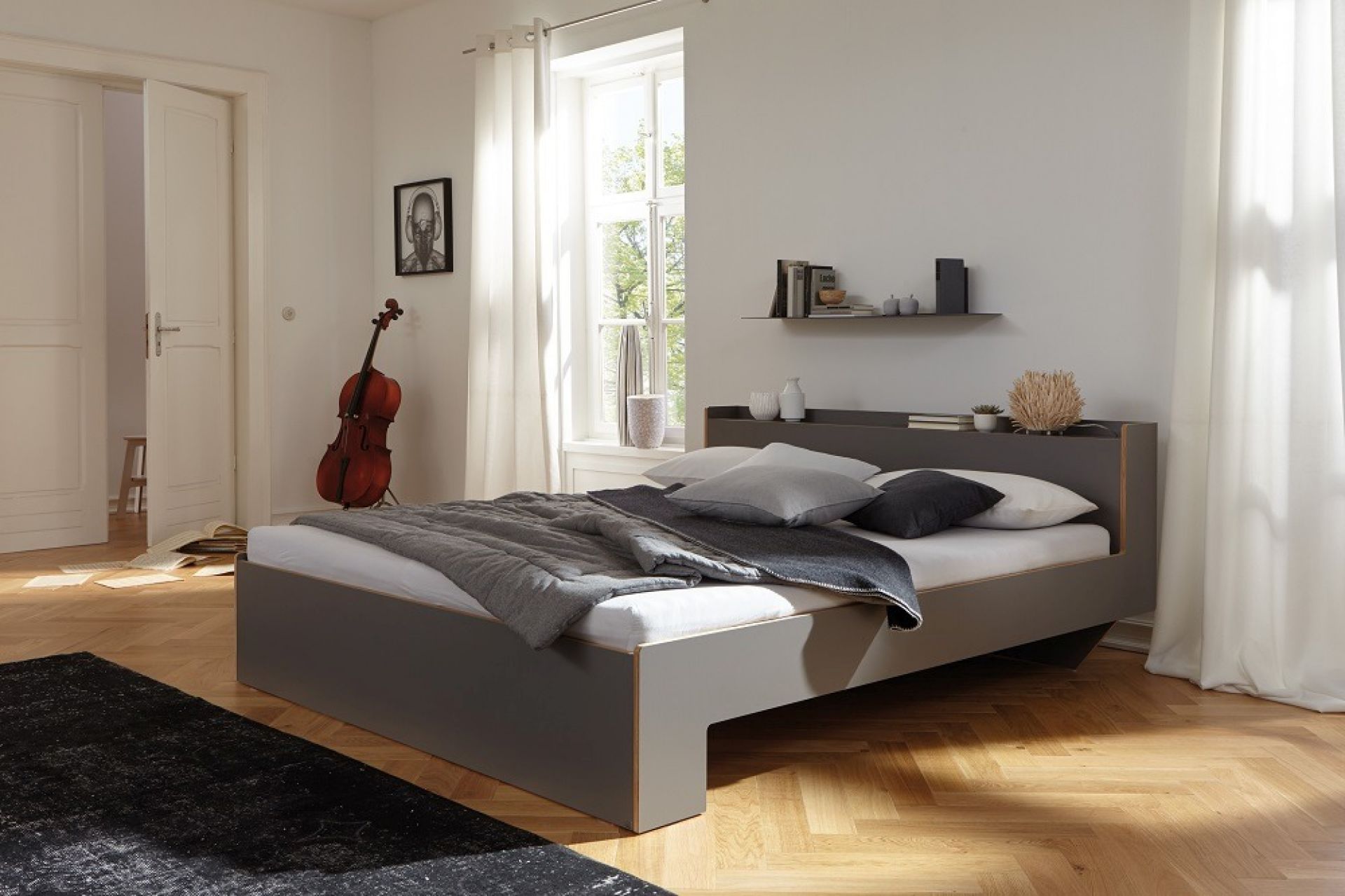 Nook Einzelbett Anthrazit von Müller Möbelwerkstätten im modernen Schlafzimmer mit Holzboden und Cello.