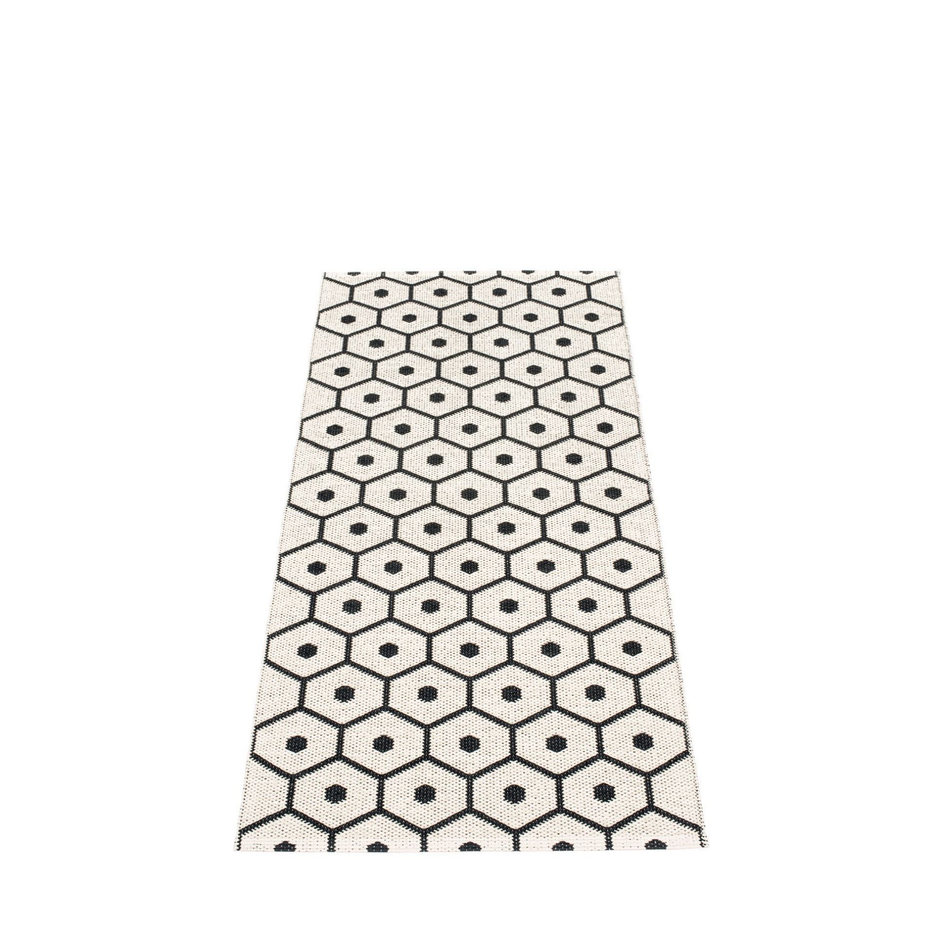 Pappelina Honey Kunststoffteppich 70x160 cm mit grafischem Wabenmuster in Schwarz und Beige.