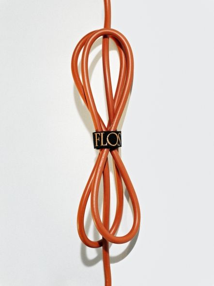Detailaufnahme des orangefarbenen Kabels der Bilboquet Tischleuchte von Flos mit schwarzem Kabelbinder.