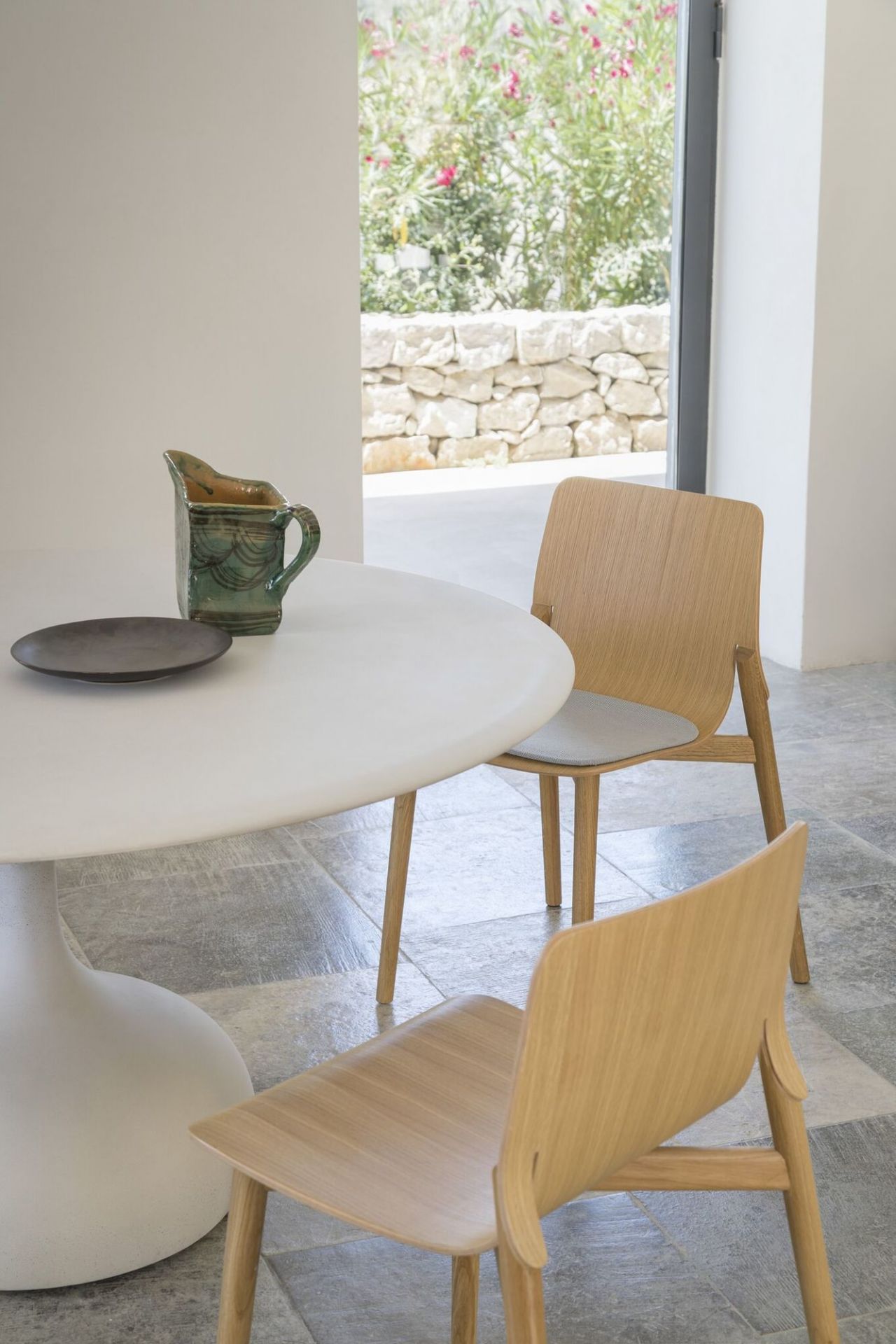 Zwei Kayak Holzstühle am Esstisch, minimalistisches Design, helle Holzoberfläche und grauer Sitzbezug.