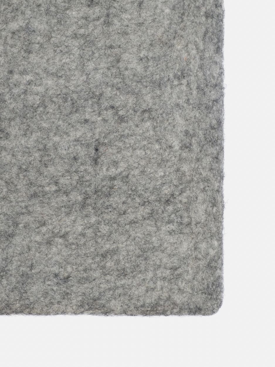 Detailaufnahme des grauen, rechteckigen Filzteppichs "myfelt Carl", der eine melierte Textur aufweist.