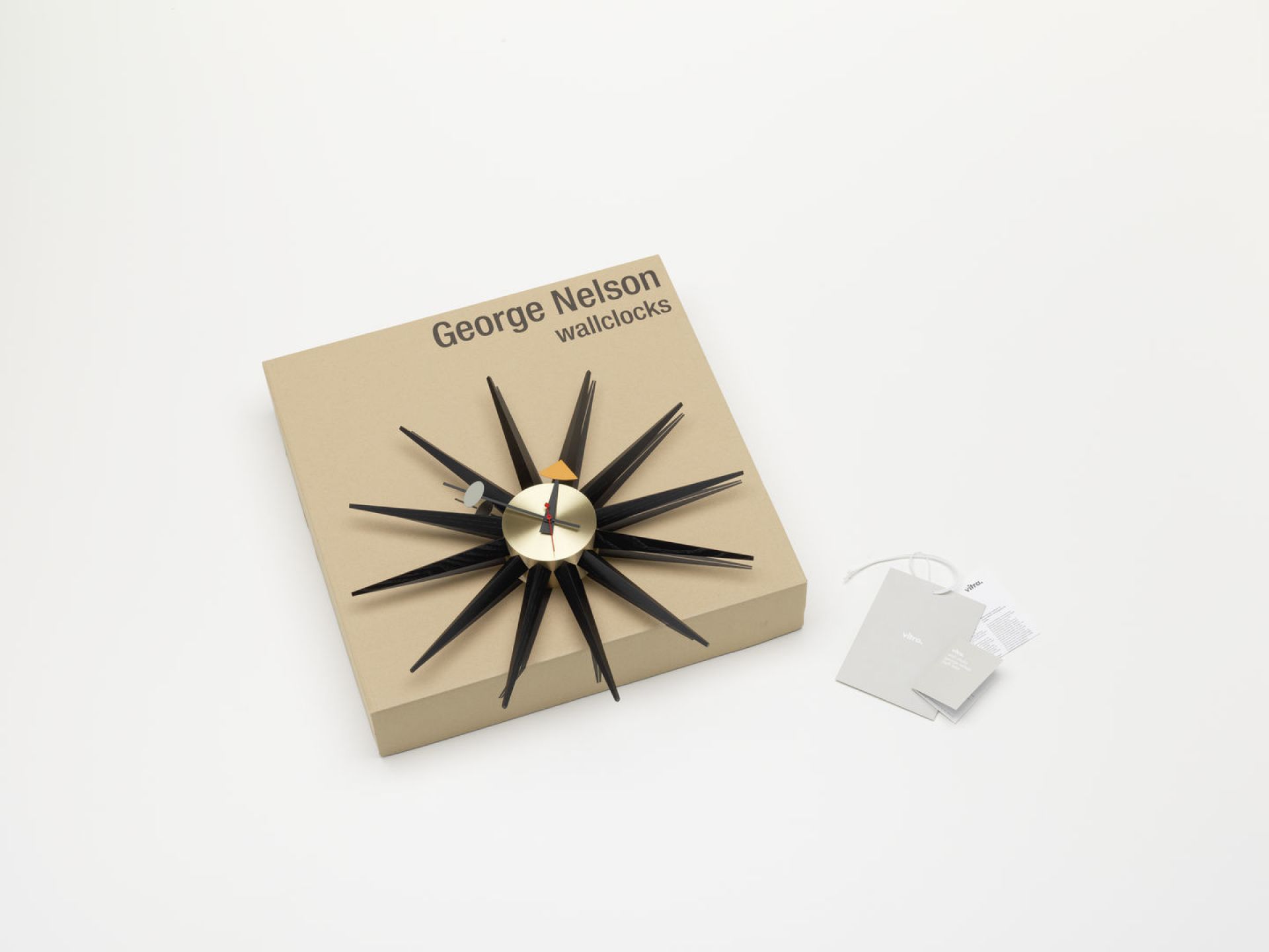 Sunburst Clock Wanduhr von Vitra, schwarze Strahlen, messingfarbenes Ziffernblatt, auf Karton.