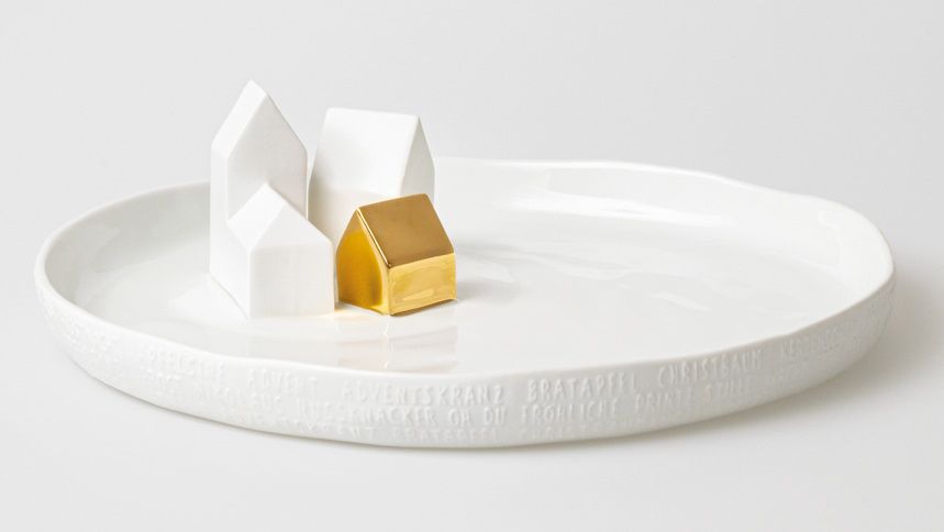 Porzellangeschichten Teller mit drei weißen Häusern und einem goldenen Haus als Deko-Objekt.