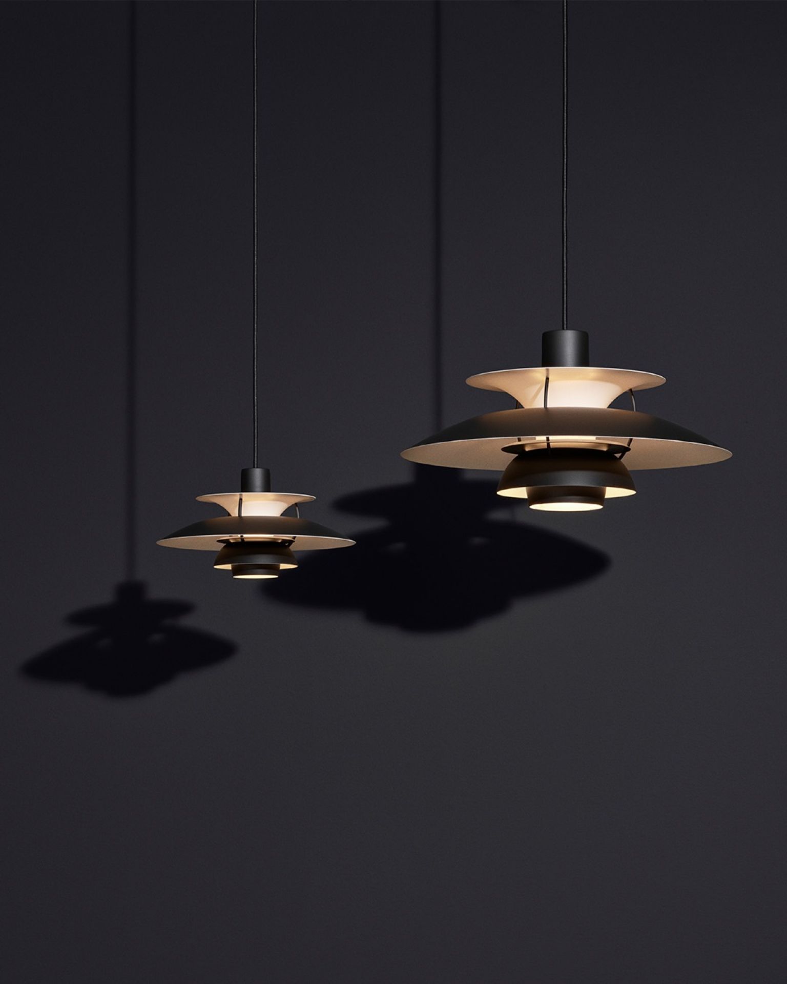 Zwei hängende PH 5 Mini Pendelleuchten von Louis Poulsen in monochromem Schwarz. Designleuchten für Wohnraum.