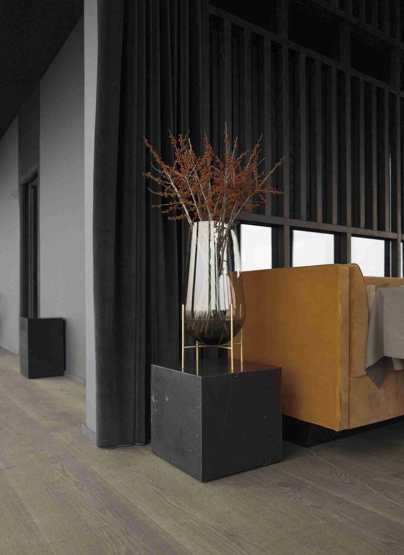 Audo Copenhagen Plinth Tisch aus Marmor mit Glasvase und Zweigen im modernen Wohnzimmer.