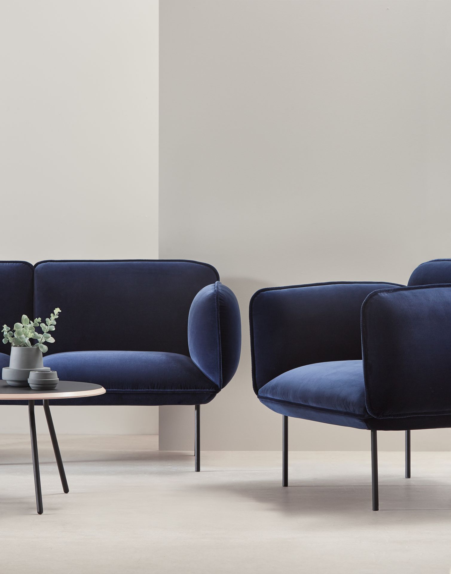 Soround Coffee Table von Woud, runder Couchtisch aus schwarzem Metall mit Dekoration und blauen Samt-Sesseln.