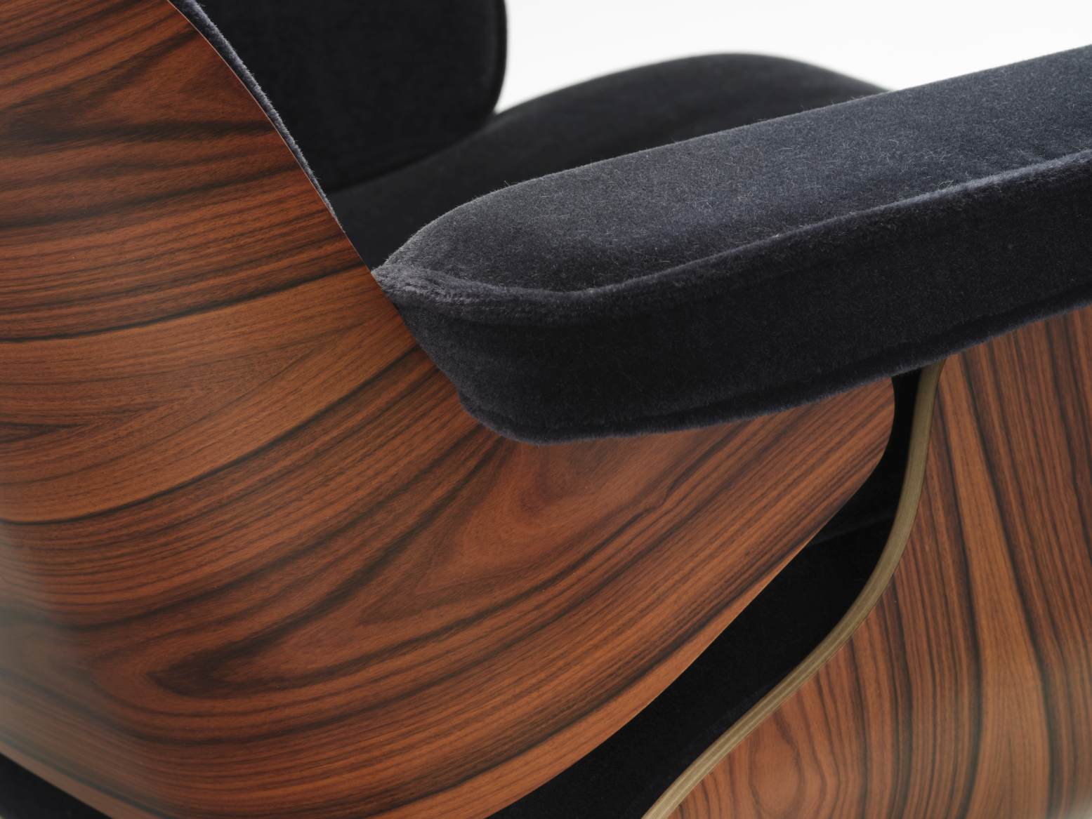 Detailaufnahme von Armlehne und Holzschale des Eames Lounge Chair Sessels mit schwarzem Lederbezug.