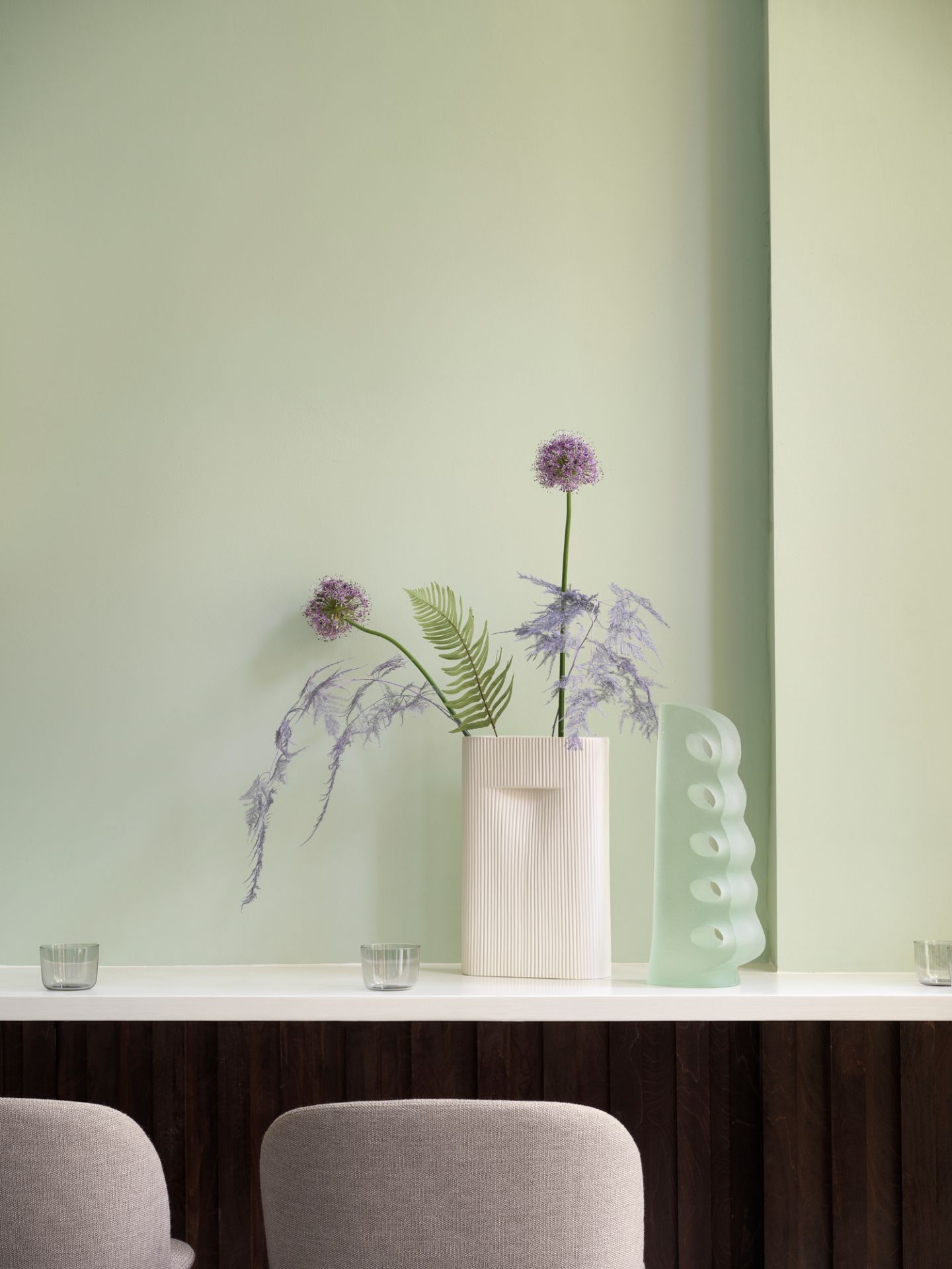 Muuto Oslo Barhocker in Grau vor einer mintgrünen Wand mit dekorativen Vasen.