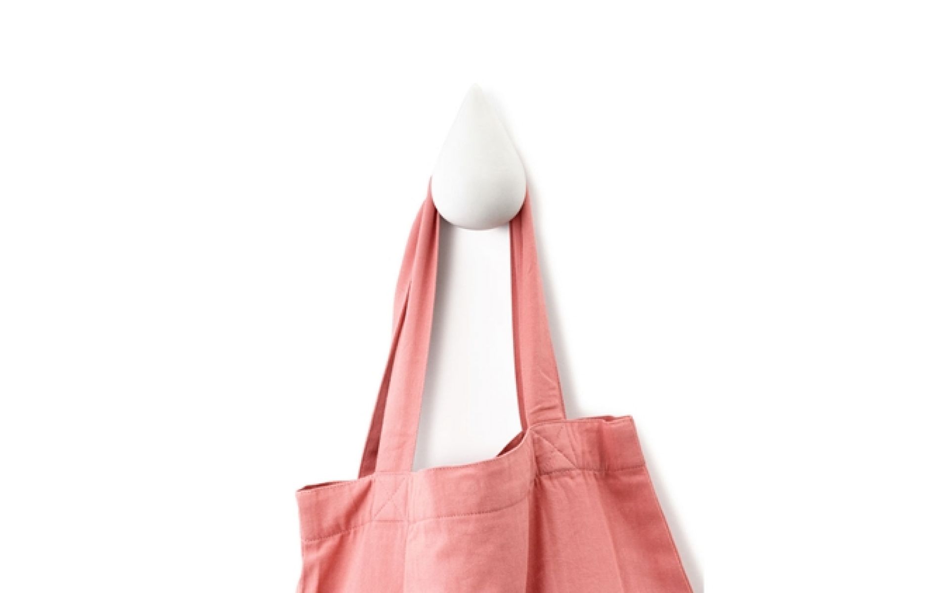 Weißer Dropit Haken von Normann Copenhagen mit einer rosafarbenen Stofftasche, moderne Garderobenhaken für Flur und Zimmer.