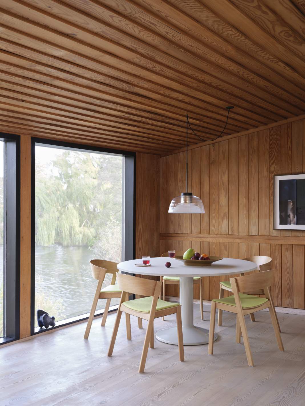 Heller Essbereich mit Muuto Esstisch, runder Tischplatte, Holzstühlen und Blick auf den See.