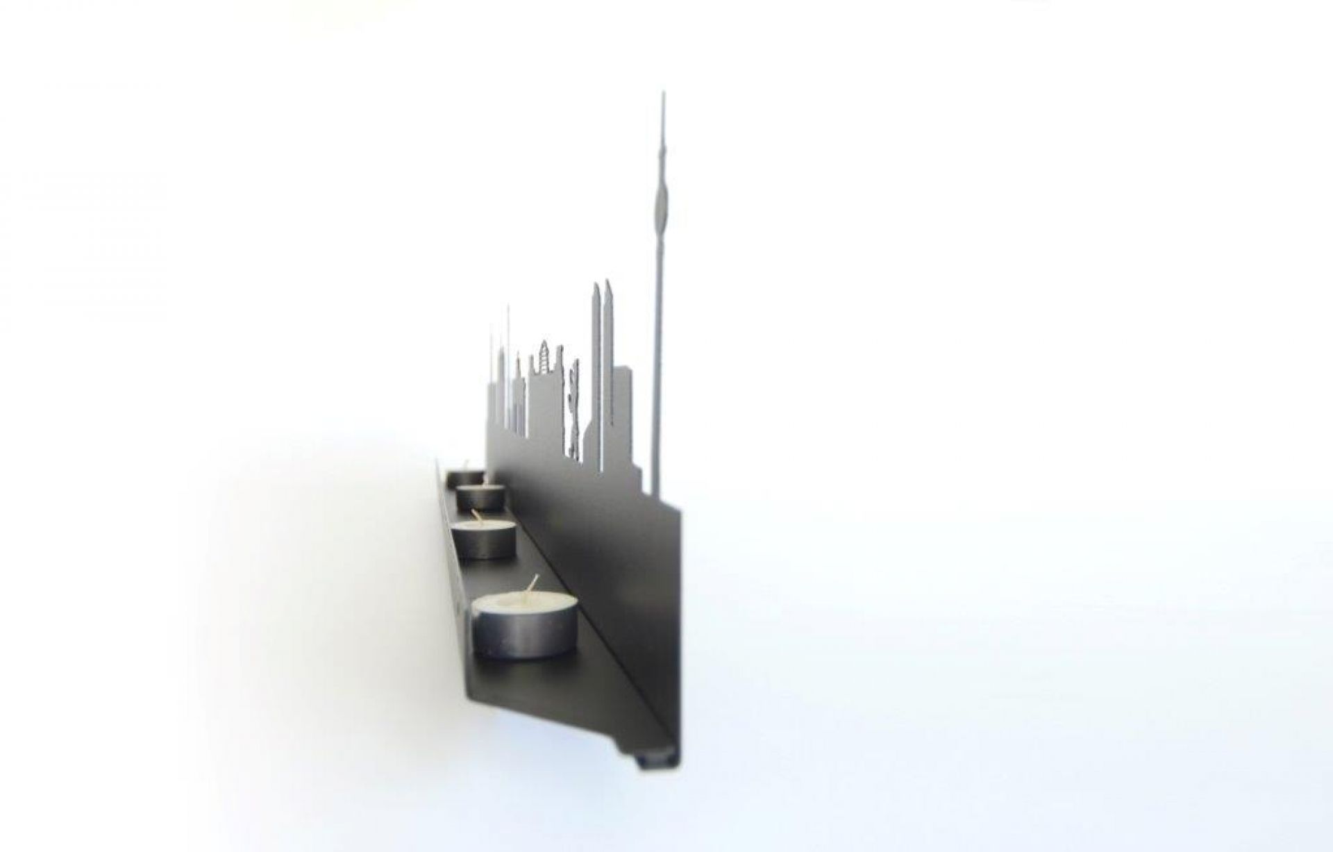 Schwarzer Licht City Kerzenständer mit Skyline-Motiv und Teelichtern vor weißem Hintergrund. Dekorative Wohnaccessoires.