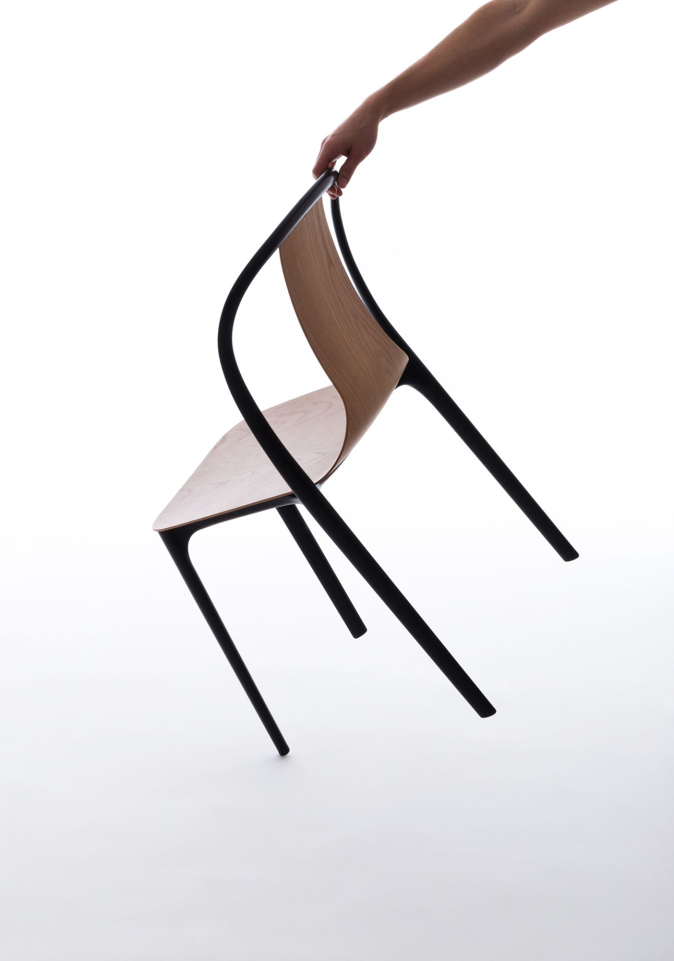 Belleville Chair von Vitra: Hand hält modernen Stuhl mit Holzschale und schwarzem Gestell.