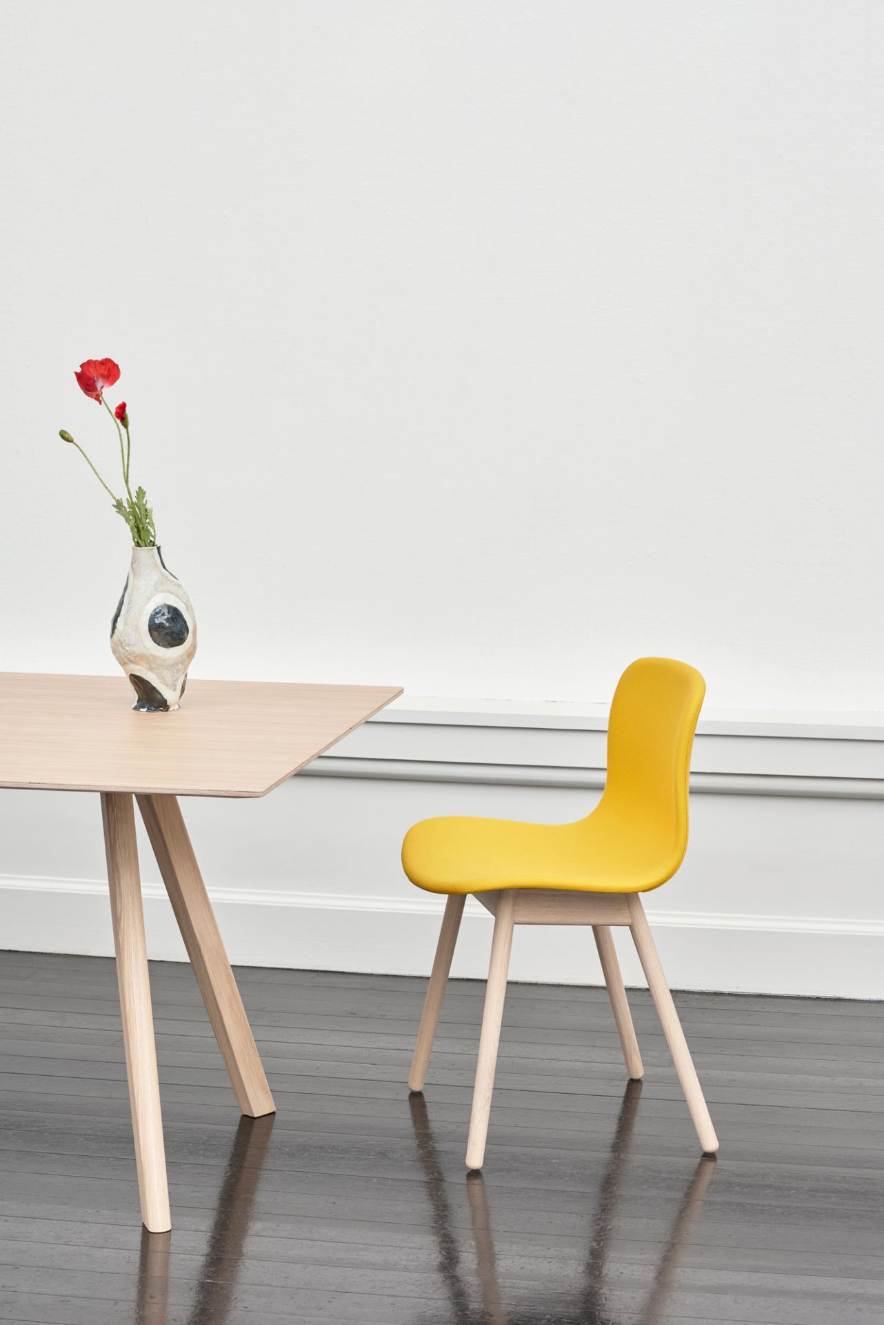Heller Copenhague Tisch CPH 30 von Hay mit gelbem Stuhl und Blumenvase im minimalistischen Raum.