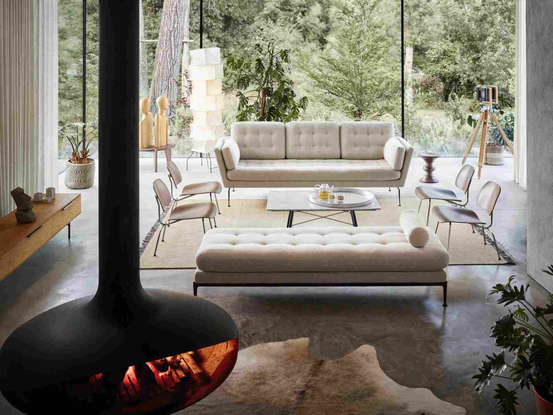 Helles Wohnzimmer mit Vitra Suita Sofa, Sesseln, Ottomane, Kamin und Blick in die Natur.