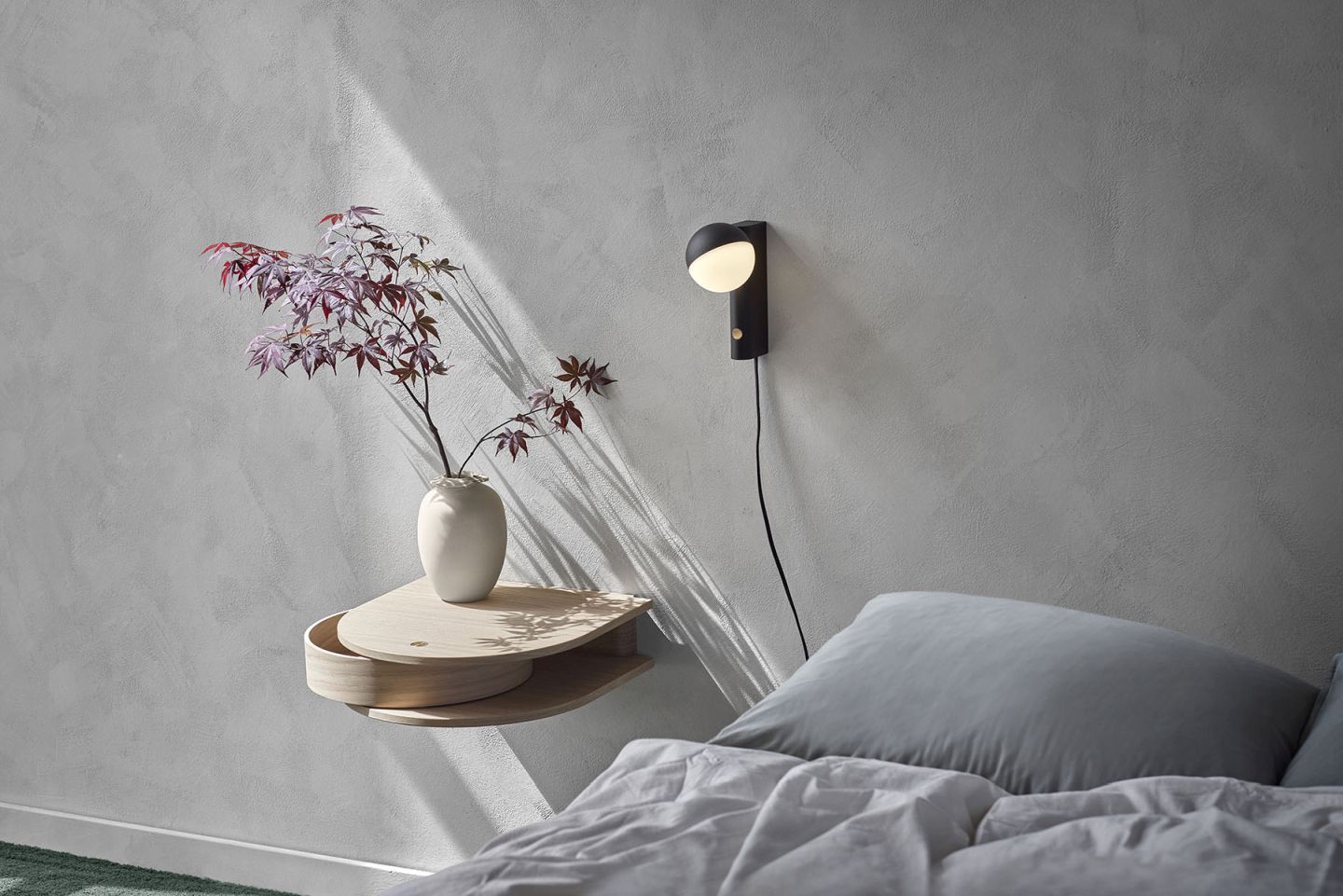 Valet Wandschublade aus geräucherter Eiche neben einer Wandleuchte im Schlafzimmer mit Bett und Dekoration.