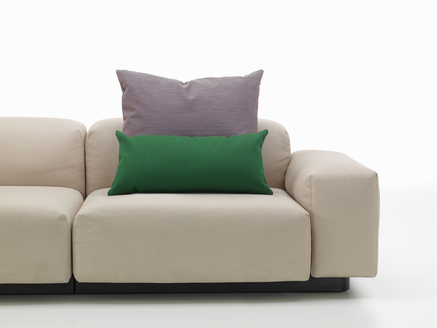 Beige Couch mit einem grünen und einem lila Vitra Kissen, Sofakissen für Wohnzimmer und Lounge.