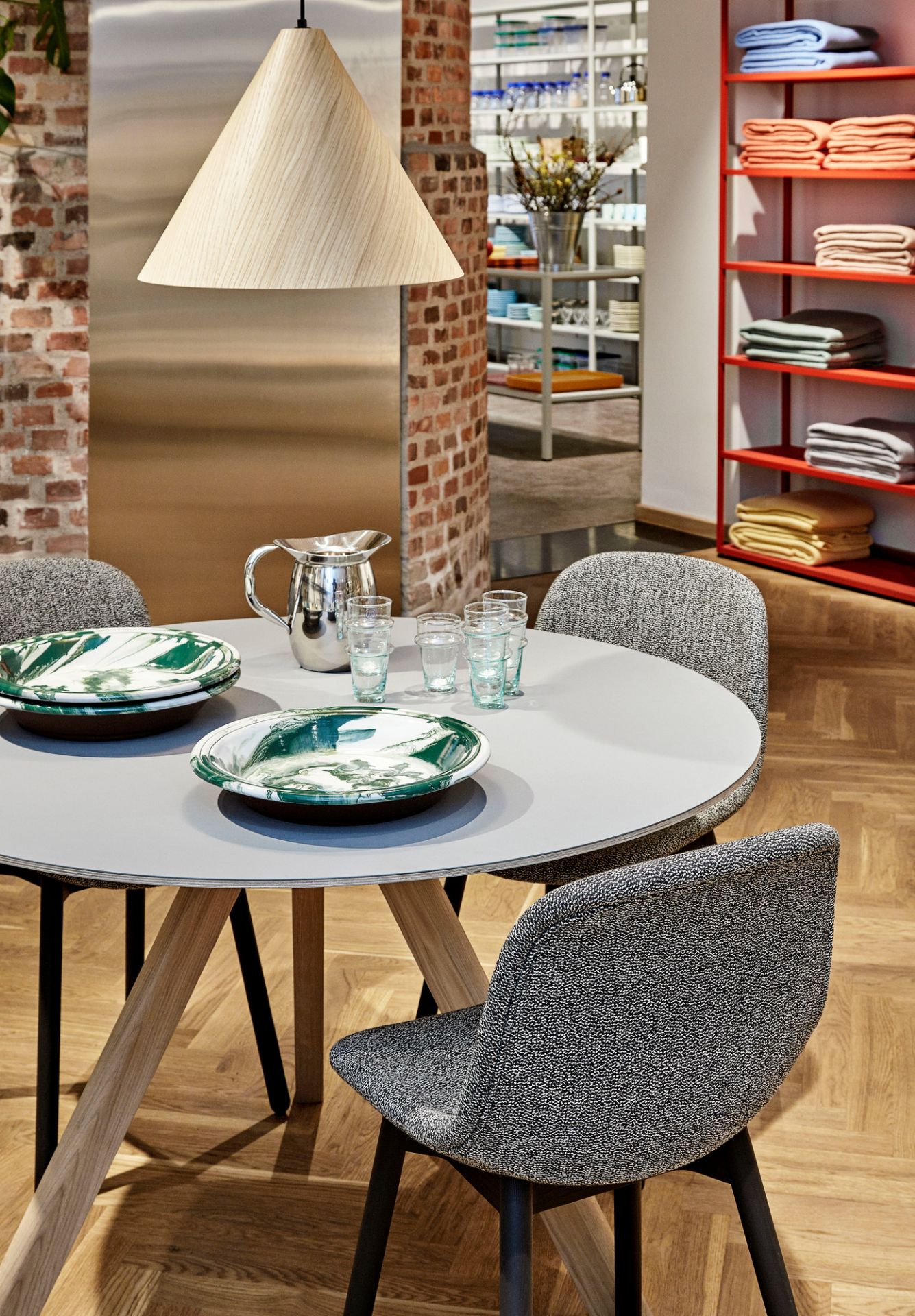 Runder Copenhague Table CPH 20 Tisch von Hay mit Geschirr und Stühlen in einem modernen Esszimmer.