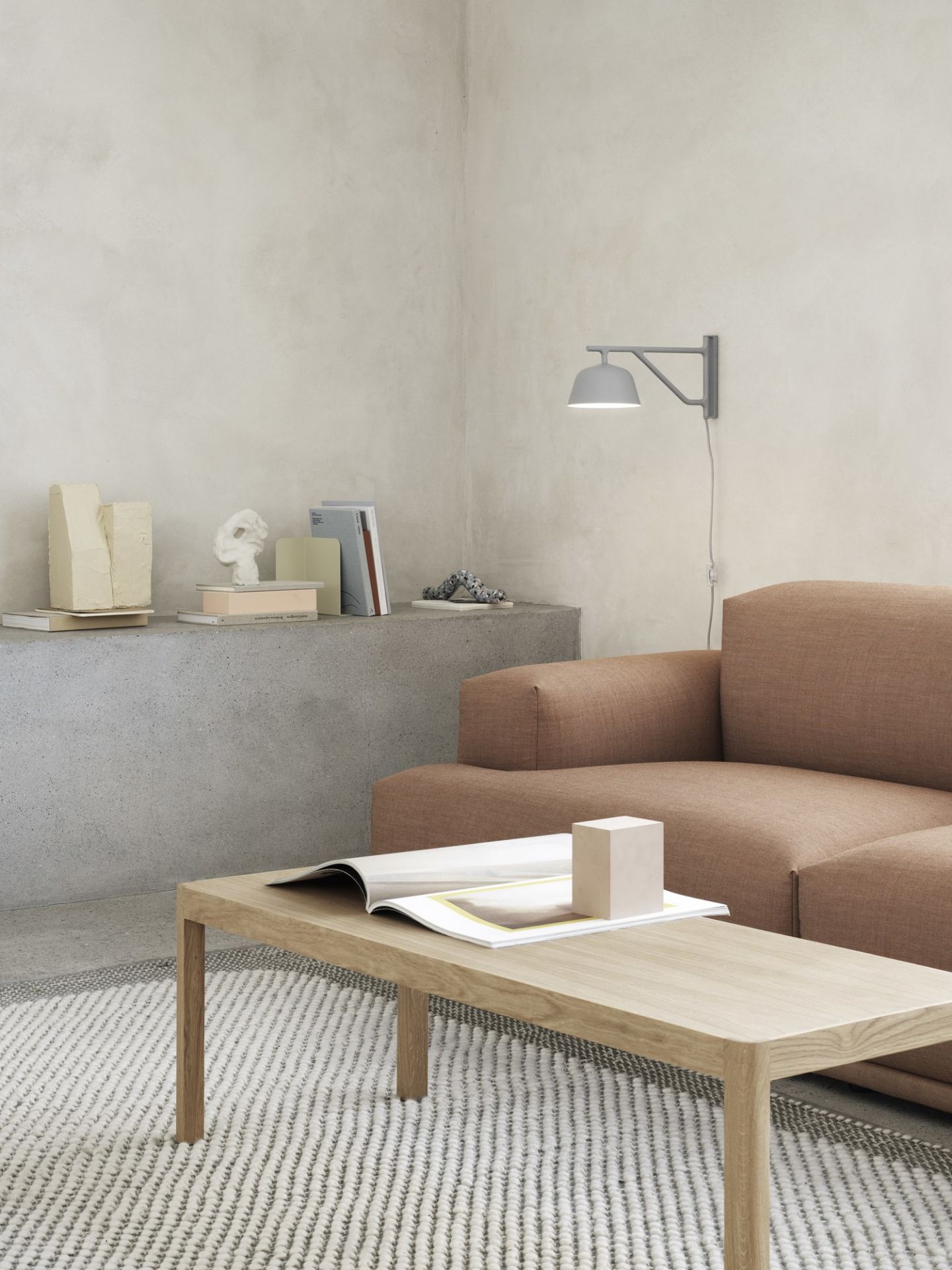 Graue Ambit Wandleuchte von Muuto über Sofa im Wohnzimmer, modernes Design für indirekte Beleuchtung.