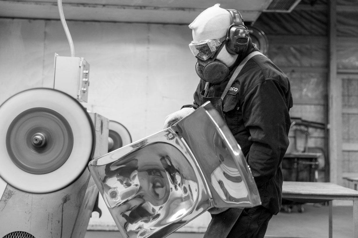 Arbeiter poliert einen Emeco Navy Chair Stuhl aus Aluminium in einer Fabrik.