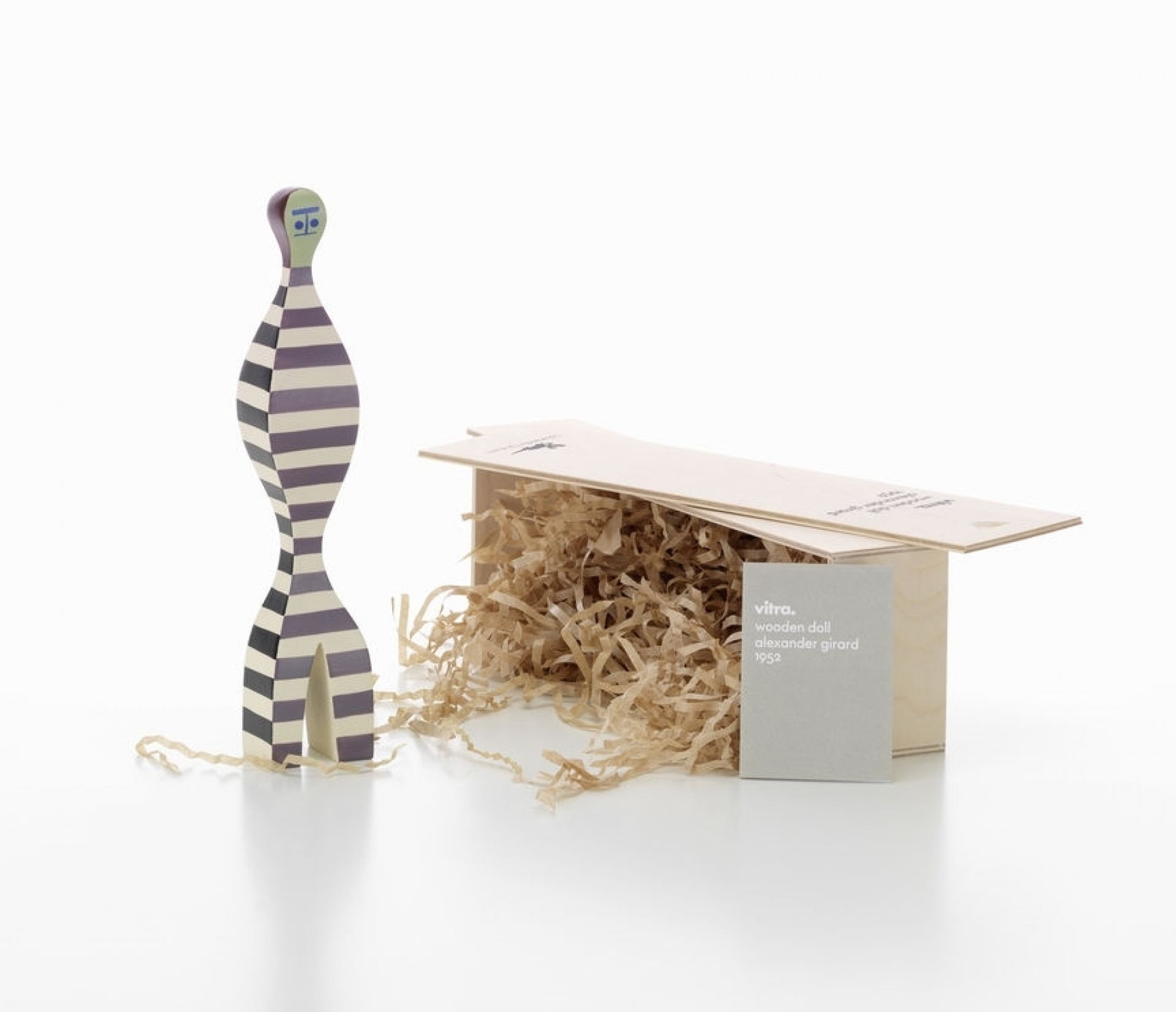 Vitra Wooden Doll No. 16, handbemalte Holzfigur mit Streifenmuster, neben offener Holzbox mit Füllmaterial.
