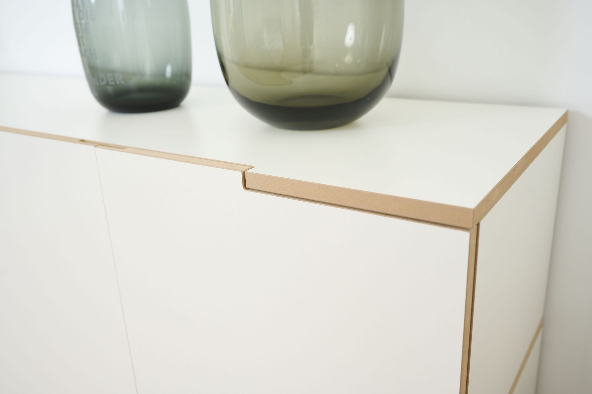 Detailaufnahme des weißen Tojo Stau Sideboards mit zwei grauen Glasvasen auf der Oberseite.