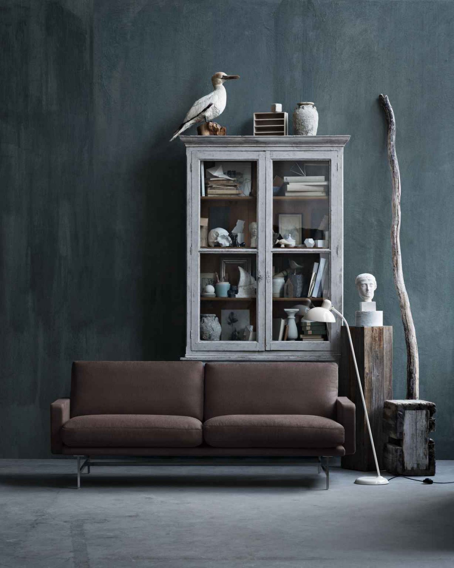 Braunes Lissoni Sofa von Fritz Hansen vor antikem Schrank und Stehlampe in Wohnraum-Szene.