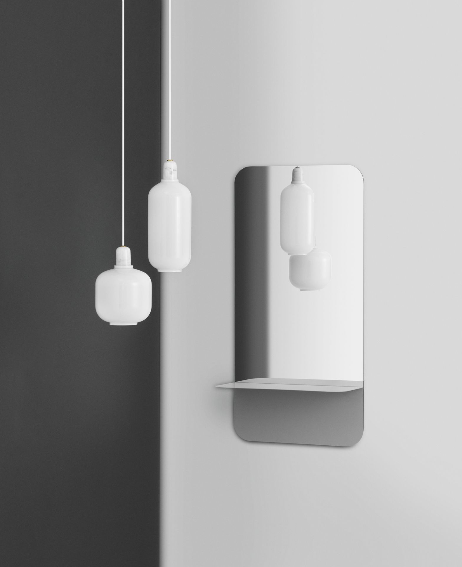 Zwei weiße Amp Lamp Pendelleuchten von Normann Copenhagen vor einer grauen Wand und Spiegel.