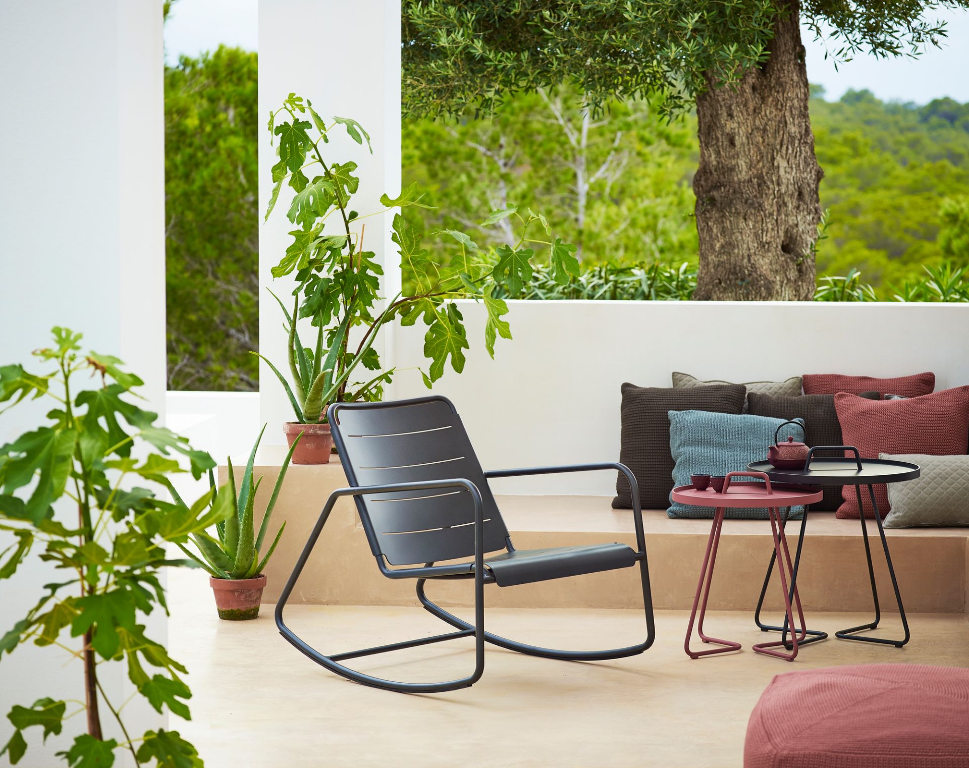Cane-Line Copenhagen Schaukelstuhl im Außenbereich, modernes Design, graues Metallgestell, entspannende Gartenmöbel.