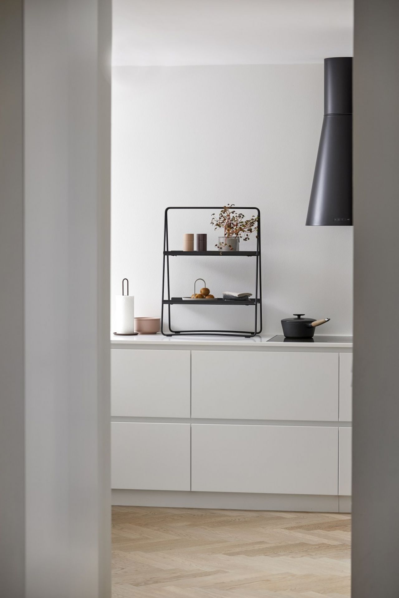 Schwarzes A-Table Regal von Zone Denmark auf einer weißen Küchenzeile mit Deko und Kochtopf.