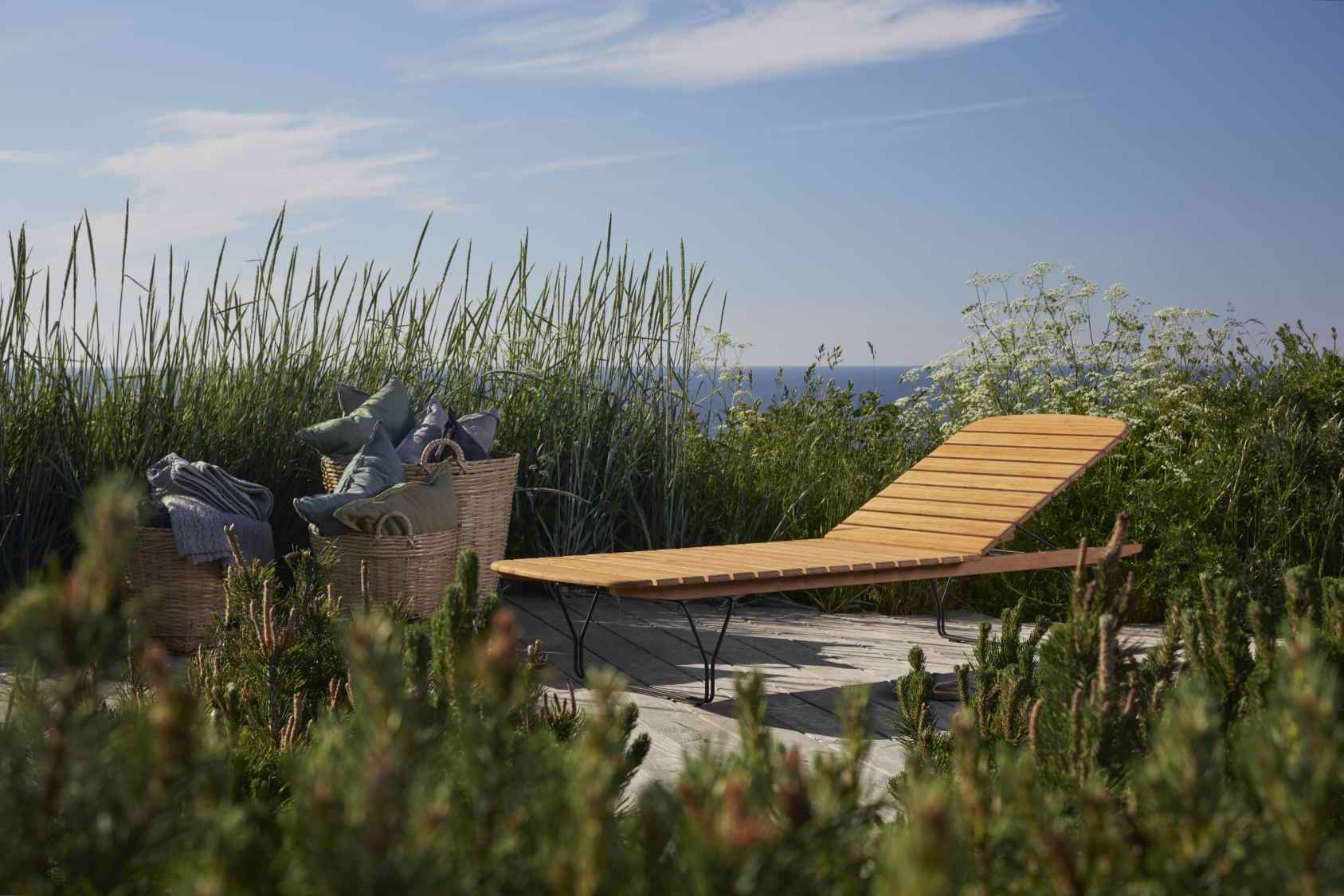Molo Outdoor Sunbed Sonnenliege von Houe aus Holz auf einer Terrasse mit Meerblick.