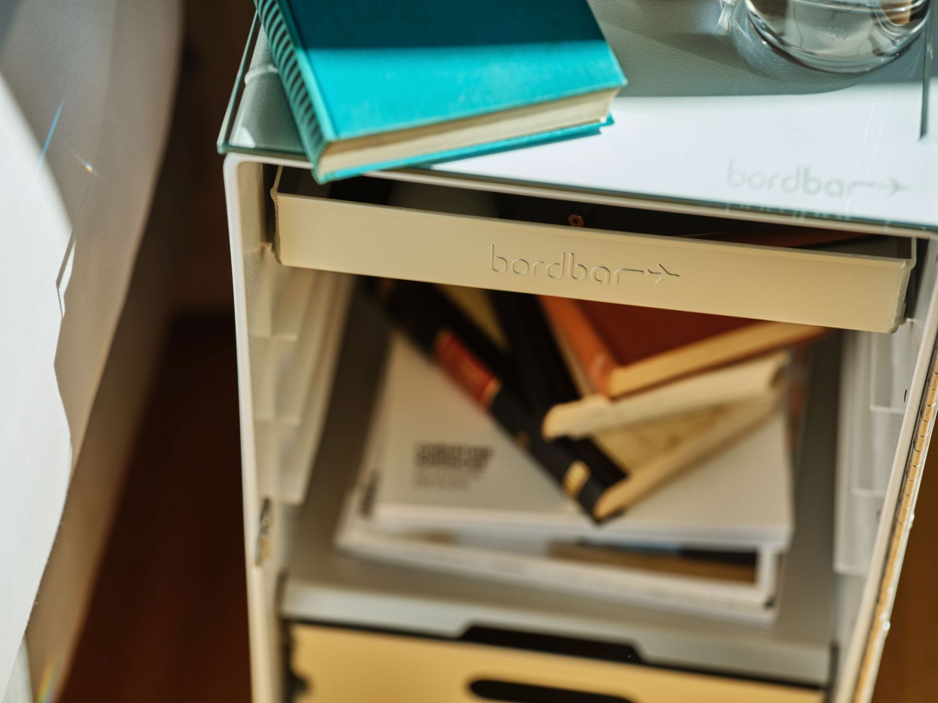 Nachttisch Bordbar mit Zubehör: Schublade offen, gefüllt mit Büchern und Ablagefläche mit Buch.