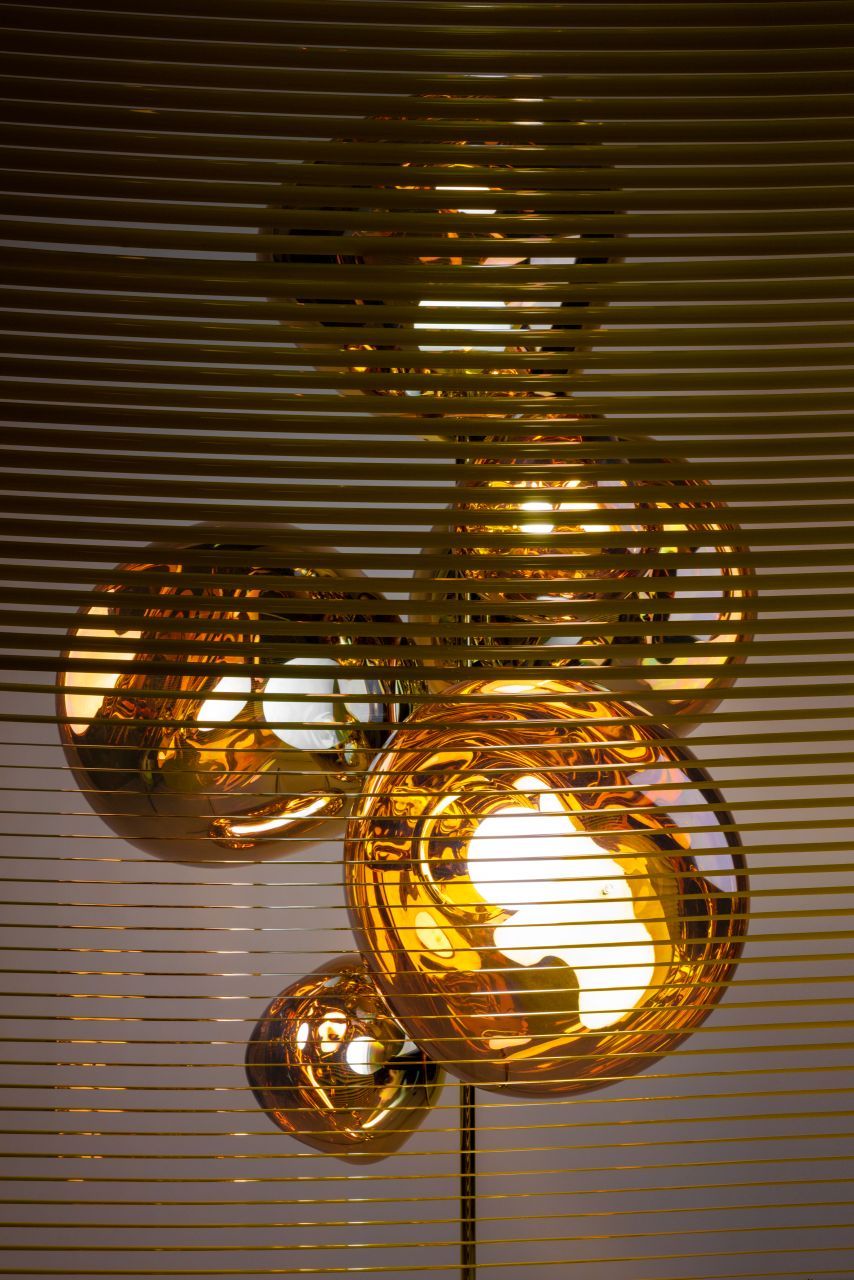 Nahaufnahme des Tom Dixon Melt Stehleuchte mit goldenen, verzerrten Kugeln und warmem Licht.