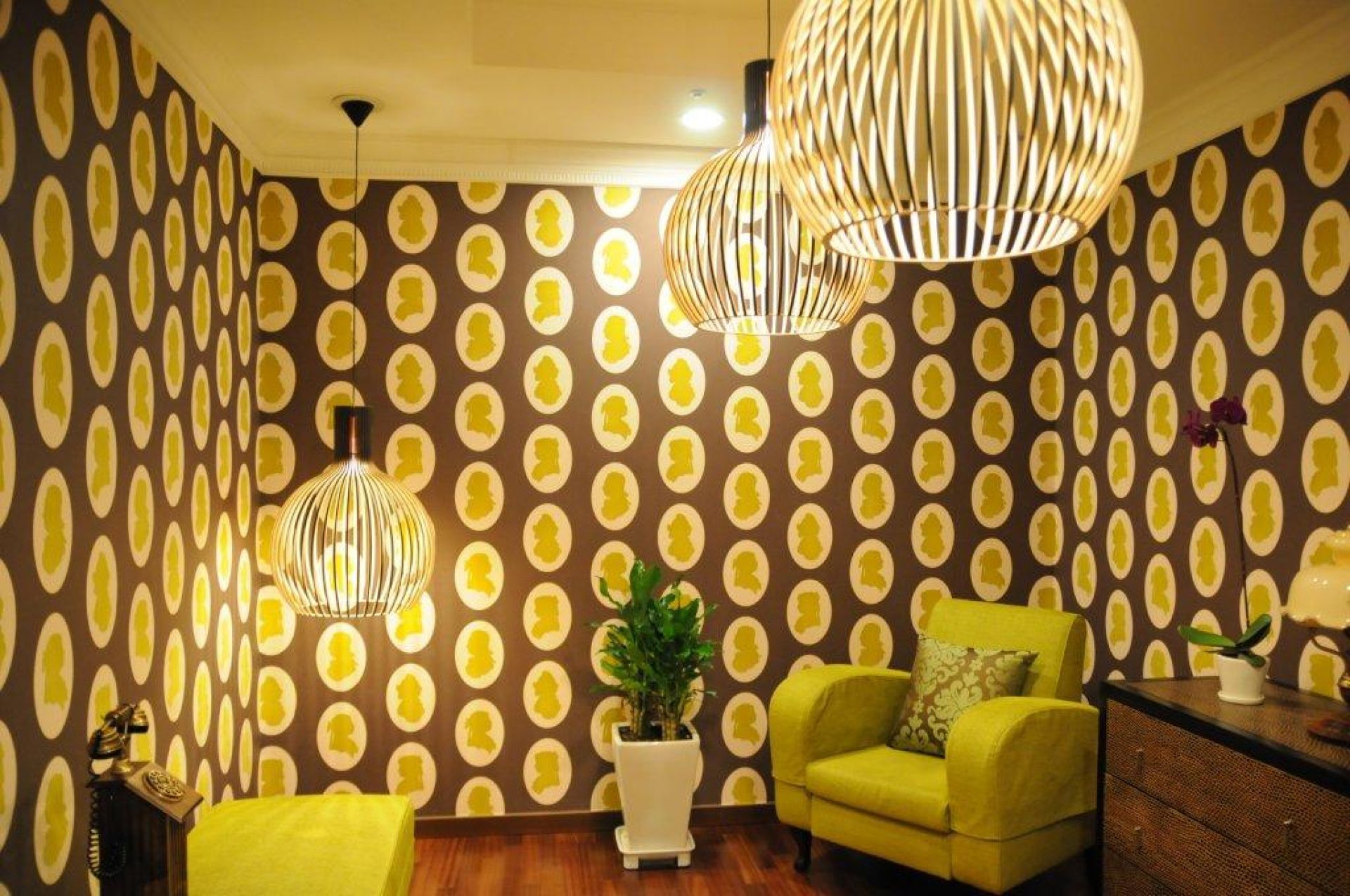 Nahaufnahme von drei Octo Pendelleuchten von Secto Design, die in einem Wohnzimmer mit Mustertapete hängen.