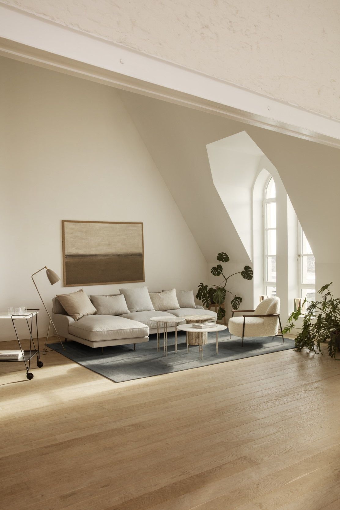 Heller Wohnraum mit Gubi Couchtisch Epic Coffee Table, Sofa, Sessel und Pflanzen.