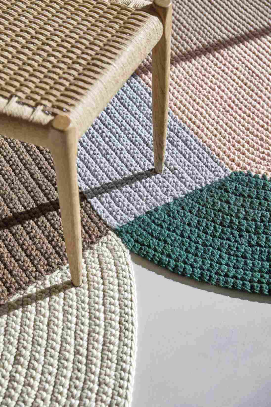 Detailaufnahme des The Crochet Collection Teppichs in verschiedenen Farben und Texturen neben einem Stuhl.
