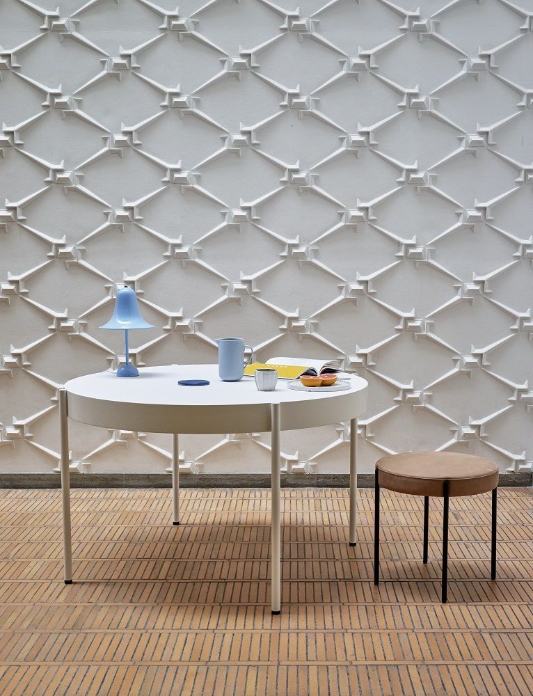 Pantop Tischleuchte in Hellblau auf einem weißen Tisch mit Dekoration, minimalistisches Design für Wohnräume.