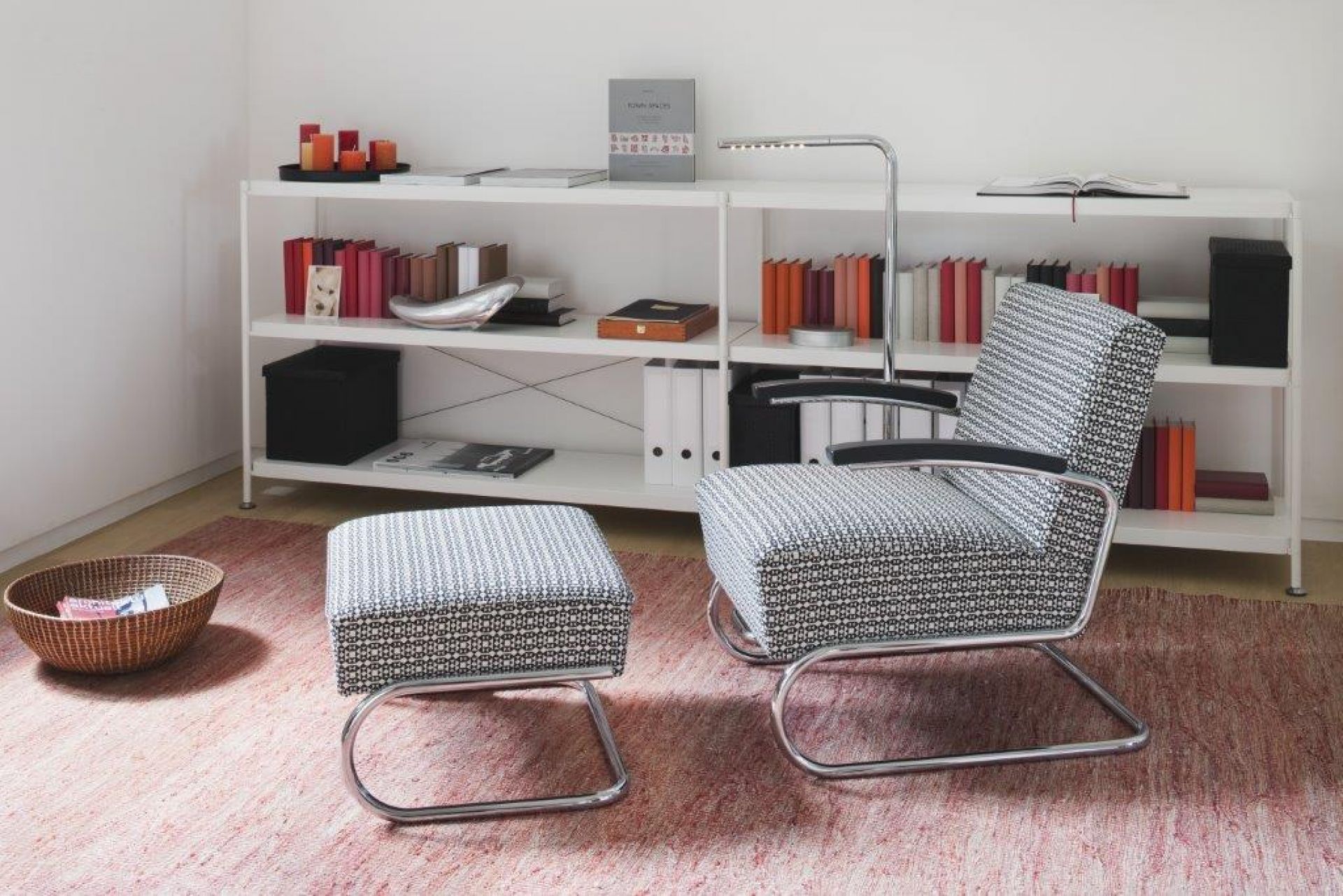 S 411 H Thonet Hocker mit Stoffbezug und verchromtem Stahlrohrgestell vor weißem Regal.
