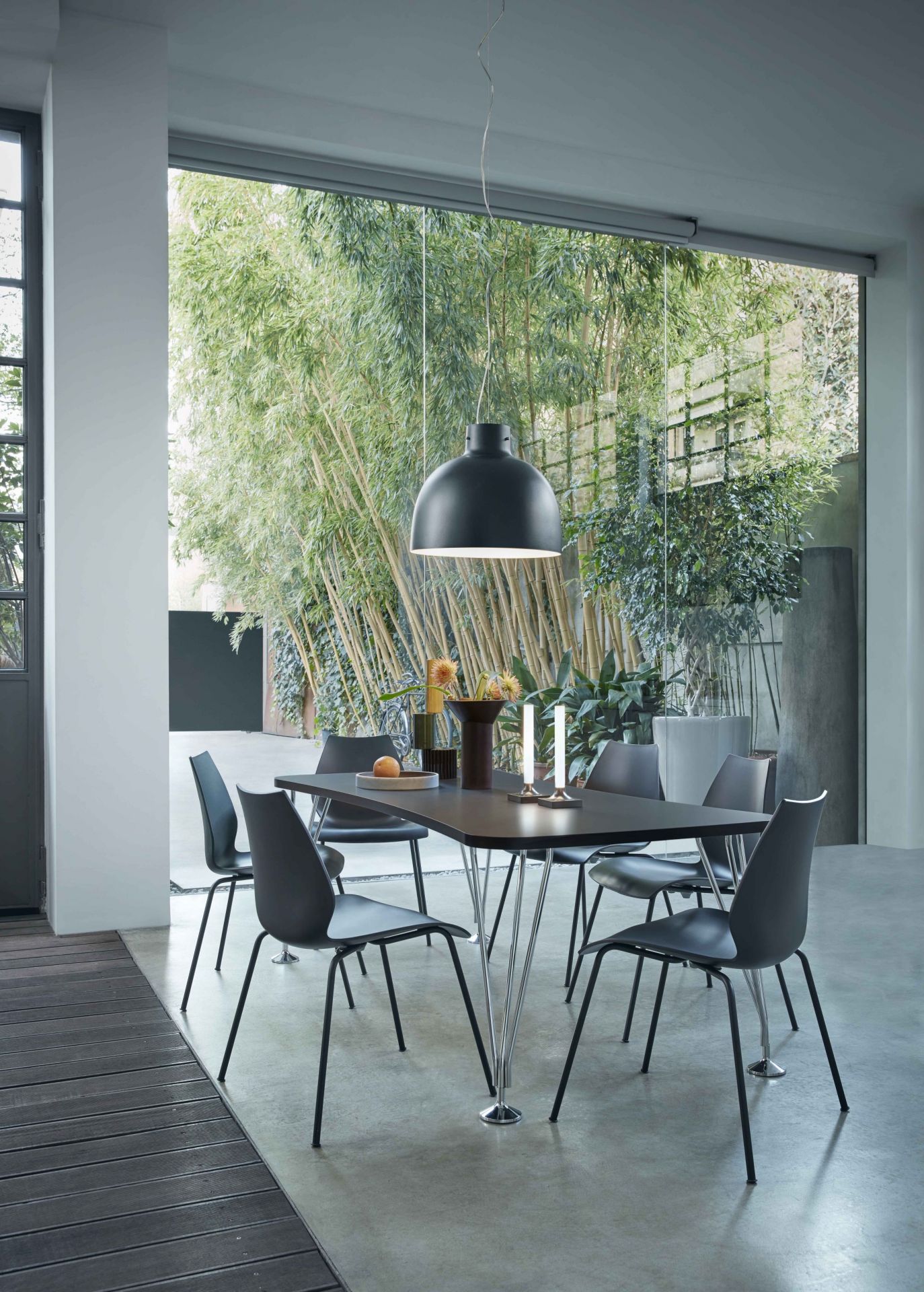 Bellissima Pendelleuchte in Grün über Esstisch mit Stühlen und Dekoration im modernen Esszimmer.