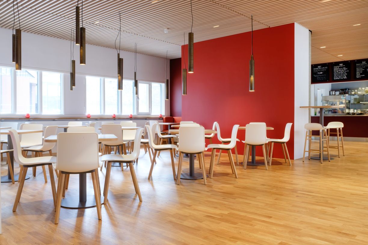 Innenraumansicht mit vielen weißen Hal RE Wood Stühlen von Vitra an Tischen.