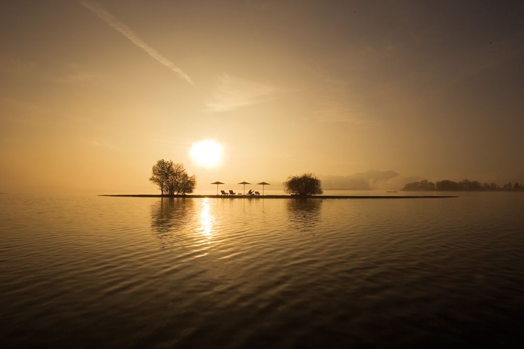 Weishäupl Sonnenschirme am Seeufer bei Sonnenaufgang, hochwertige Outdoor-Sonnenschirme für entspannte Stunden im Freien.